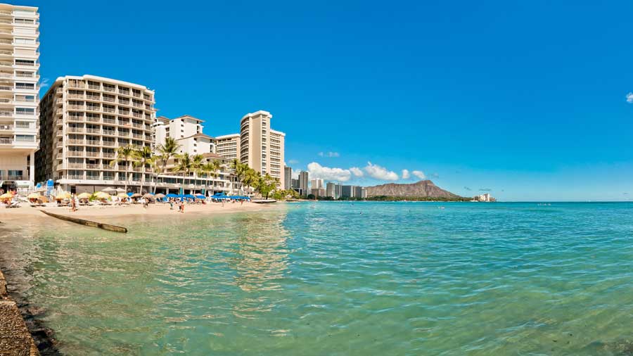 building near Waikiki shoreline with tourists in Honolulu Hawaii