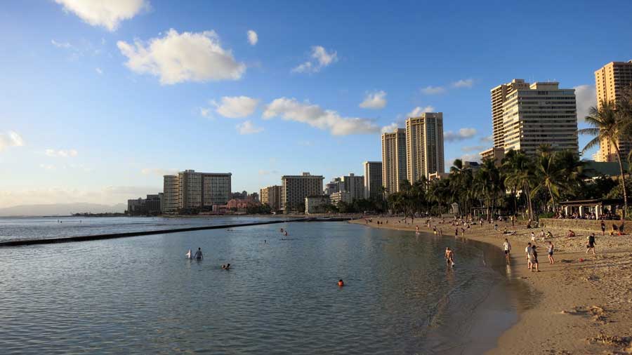 People play in the water and beach in Waikiki Hawaii